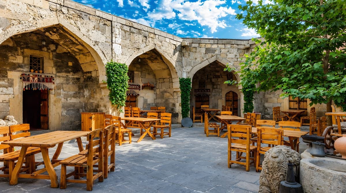 The Ocaq Alovu restaurant website homepage - a sunlit stone courtyard with wooden tables in Baku's Old City.